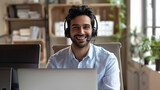 Fototapeta  - A cheerful male customer support agent with a headset working on a laptop, providing remote assistance.