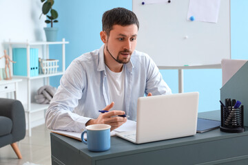 Canvas Print - Male tutor with laptop giving online lesson at home