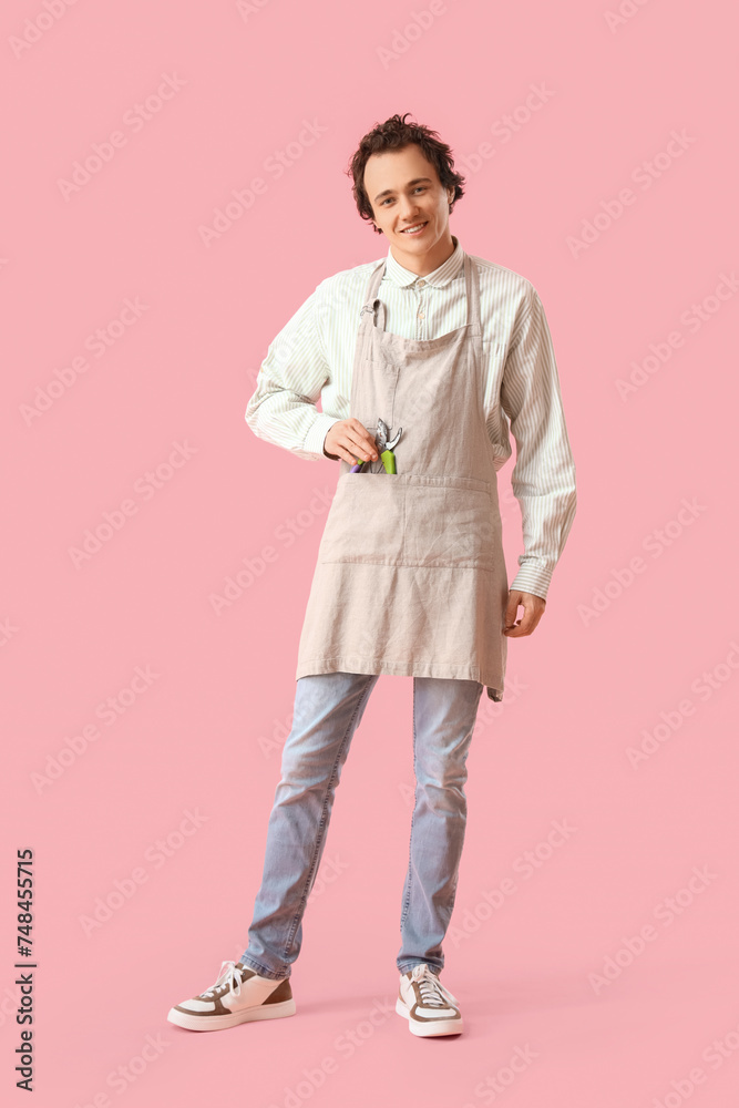 Male gardener with secateurs on pink background