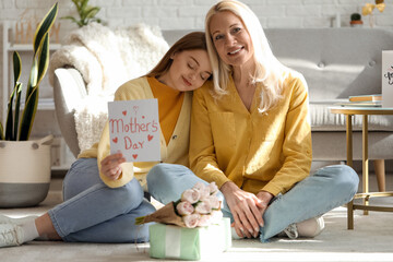 Wall Mural - Young woman greeting her mother with card at home