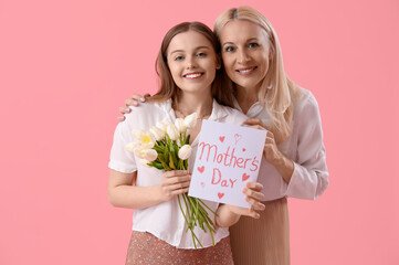 Canvas Print - Young woman greeting her mother with tulips and card on pink background