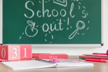 Calendar with date 31 MAY and copybooks on desk in classroom, closeup