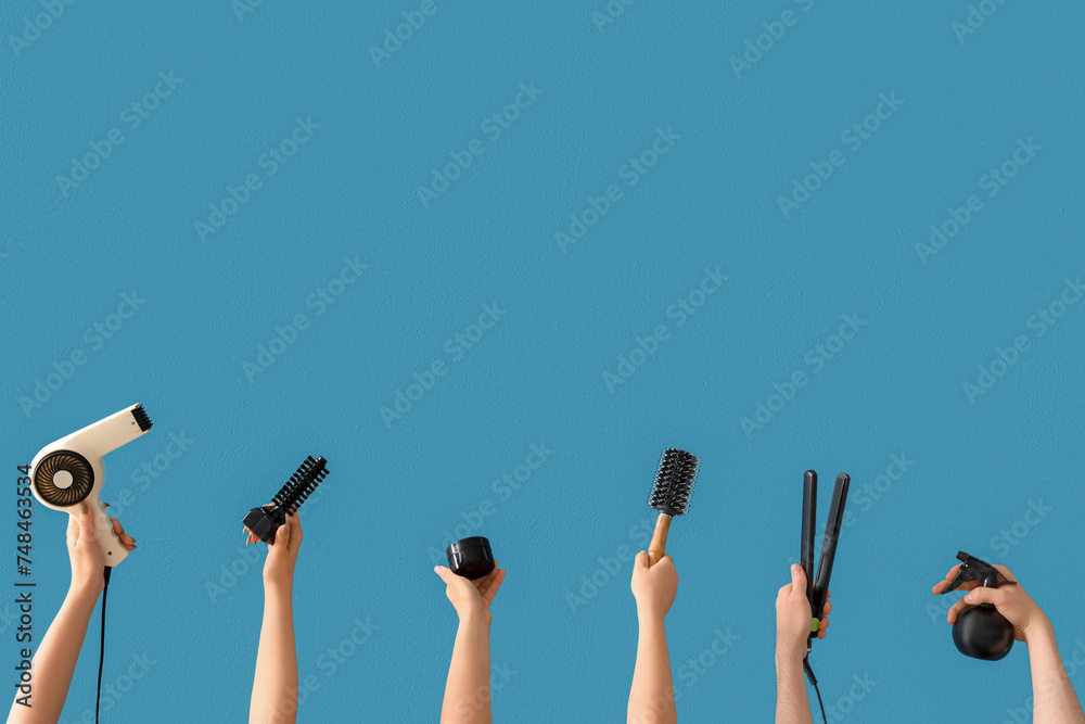 Many hands with different hairdressing supplies on blue background