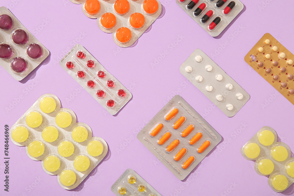 Different pills in blister packs on lilac background