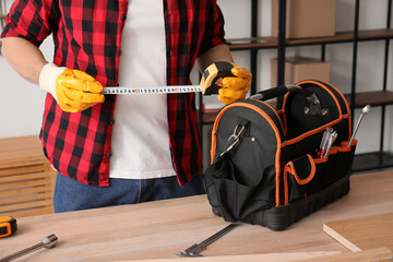 Canvas Print - Male carpenter with measuring tape and tool kit in workshop