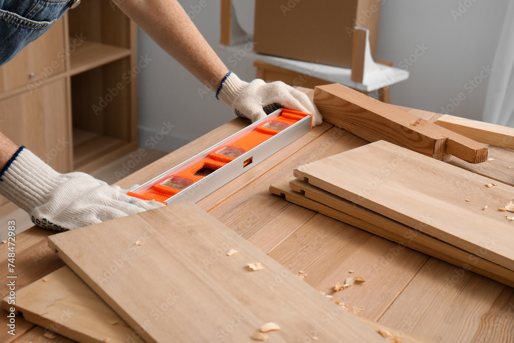 Female carpenter with spirit level on table in workshop, closeup