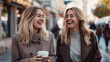 コーヒーを片手に街で談笑する2人の若い女性