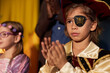 Portrait of young boy wearing pirate costume with eye patch standing on stage in theater and applauding copy space