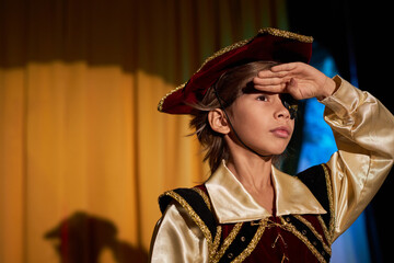 Wall Mural - Waist up portrait of boy wearing pirate costume performing on stage in spotlight and talking to audience, copy space