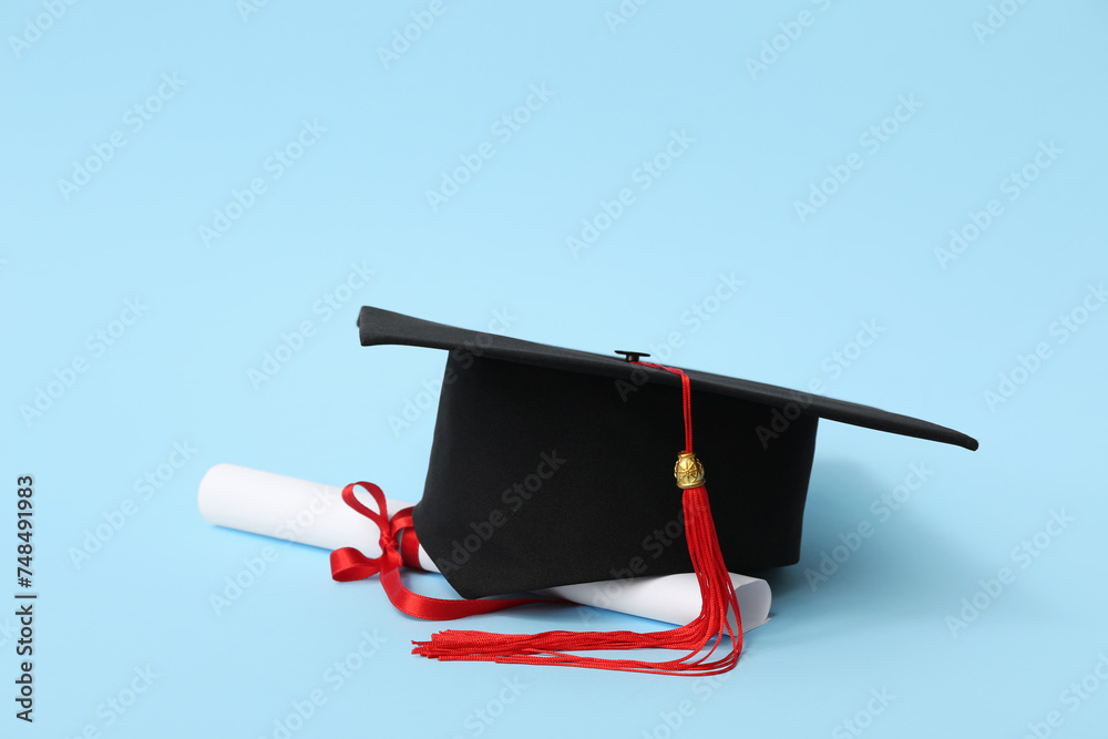 Mortar board and diploma on blue background