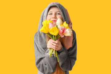 Wall Mural - Beautiful young happy woman in bunny costume with bouquet of tulips on yellow background. Easter celebration