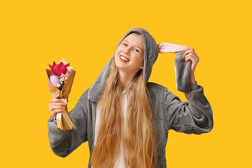 Wall Mural - Beautiful young happy woman in bunny costume with bouquet of flowers on yellow background. Easter celebration