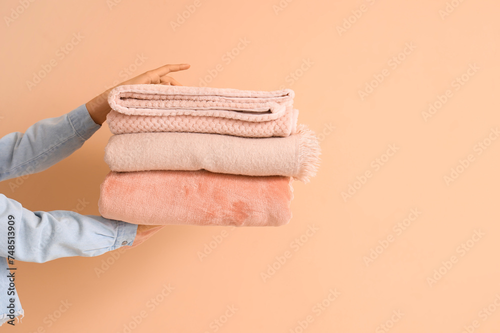 Female hands with folded warm plaids on beige background