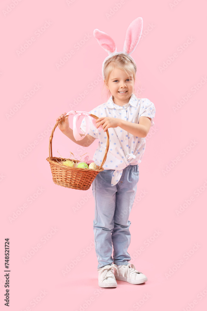 Little girl in bunny ears with Easter eggs on pink background