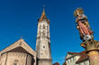 Der schiefe Turm der Johanniskirche in der Altstadt von Schwäbisch Gmünd bei sommerlichen Wetter und wolkenlosem Himmel mit der Figur der Mutter Christi des Marienbrunnens auf dem Marktplatz