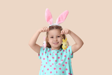 Poster - Cute little girl in bunny ears with Easter eggs on beige background