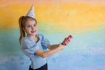 Wall Mural - Portrait of funny girl in birthday hat and bright confetti on yellow background. Celebration and party