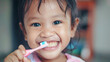 © VK Studio - Young girl happily brushing her teeth with a pink toothbrush.