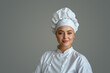 Portrait of a beautiful female chef in a white uniform on a gray background