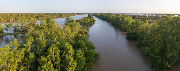 Aerial evening panoramic view of a side arm of the Ham Luong River in Vietnam's Mekong Delta, a unique landscape dominated by water, islands and tropical rainforest