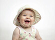 Portrait of cute newborn laughing happy baby in summer hat and dress as studio shoot on pastel colors background