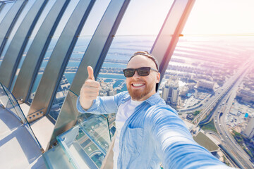 Wall Mural - Selfie photo of happy young man tourist background skyscrapers in Dubai, UAE tourism travel