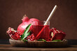 Fresh juice of pomegranate with fruit and leaves on wooden plate on dark rustick background.