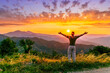 © Yaroslav - rejoicing man with beautiful scenic mountain sunset landscape on background. happy man watching amazing evening sunset
