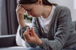 Selective focus of upset worried young woman holding wedding ring think of marriage dissolution or divorce having family problems. Unhappy sad brunette girl stressed with relationships end or breakup