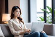 © anmitsu - Beautiful young Asian female freelancer successful in business sitting on comfortable sofa and browsing internet through laptop. She has luxury interior, work from home concept