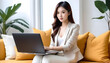 © anmitsu - Beautiful young Asian female freelancer successful in business sitting on comfortable sofa and browsing internet through laptop. She has luxury interior, work from home concept
