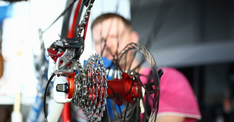 Wall Mural - Close-up of bicycle and mechanic fixing chain in protective gloves. Macro shot of red bike on repair. Metal details of transport. Vehicle maintenance and workshop concept