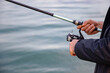 © Yelena - Fisherman holding a fishing rod on the background of the sea
