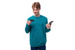 © Ivan Traimak - handsome red-haired young man in a blue sweater holds a credit card and a smarfton. e-business concept