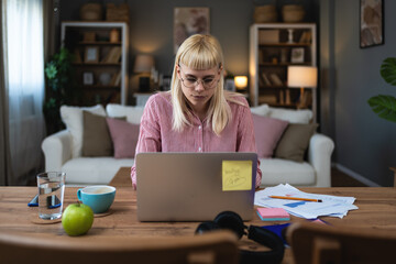 Young business woman research for her new job and employer from home office on laptop. Female businessperson surfing the internet for solutions and improvement of her small company digital marketing