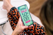 Spring sales offer Ad. Up to 50% off. Woman holding a mobile phone showing an offer or coupon on the screen.