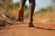 a close up of a black african childs foot as they walk barefoot along a dirt road