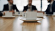 © FutureProof - Close-Up of Coffee Cups on a Conference Room Table in Front of Business People Talking