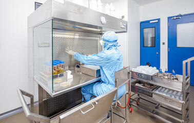 microbiologist in a laboratory working with petri dish in the microbiology laboratory, microbiologist scientist, while at his workplace in a research laboratory study a flask / beaker in a cleanroom