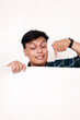 © ArvStd - Portrait of young asian man standing behind an empty signboard and pointing on it