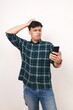© ArvStd - Confused young asian man standing while using a cell phone
