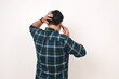 © ArvStd - Back view of young asian man talking on the phone while holding his head
