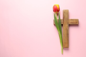 Wall Mural - Easter - celebration of Jesus resurrection. Wooden cross and tulip on pink background, top view. Space for text