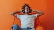 © Nataliya - Handsome man listening to music while sitting in comfortable armchair against color wall