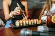 Person Holding Chopsticks Over Plate of Sushi
