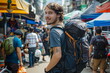 Portrait of a young man standing in the middle of a big crowd with a backpack