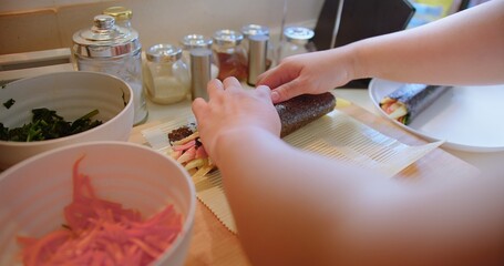 Wall Mural - chef hand cooking korean traditional recipe food making kimbap warp fresh ingredient seaweed rice meal vegetable on bamboo roll at home kitchen, delicious asia sushi cuisine