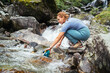 © Soloviova Liudmyla - Young woman trekker crossing mountain river and filling ip fresh water in touristic bottle during Makalu Barun National Park trek in Nepal. Mountain hiking and active people concept image