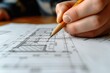 Hand drawing on blueprint with pencil, building layout visible. Designer adjusting details.