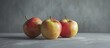 Three ripe apples are placed side by side on a flat wooden table, their shiny skins reflecting the soft light in the room.